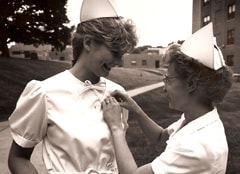 Older photo of nurse pinning a new nurse.