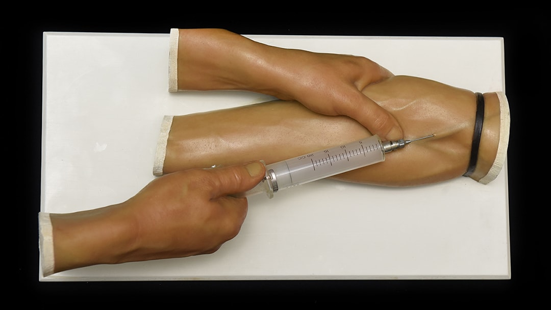 Student inserting an IV into a model arm.