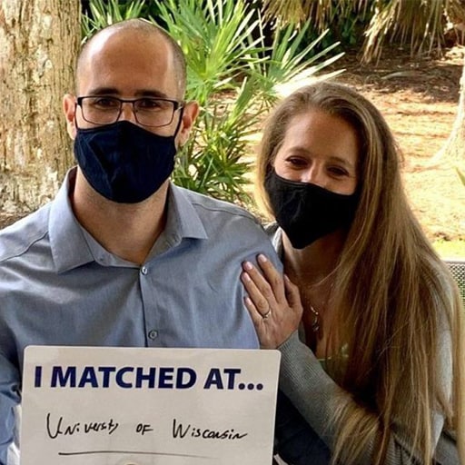 Photo of Nick Rubel and wife sitting on a bench holding a sign of where he matched to a residency during Match Day celebrations at Mayo Clinic.