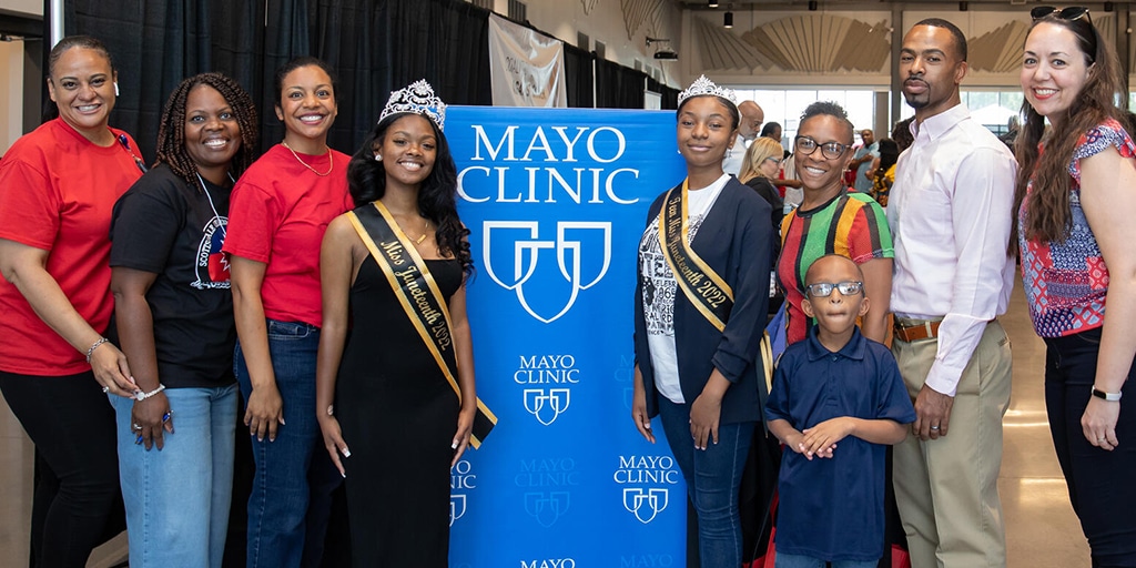 Shaundrea Norman, Miss Juneteenth 2022, and Kendall McCollum, Miss Teen Juneteenth 2022, pose in front of the Mayo Clinic booth with staff. Asset taken to document the City of Scottsdale Community Juneteenth Celebration presented by the Mayo Clinic.