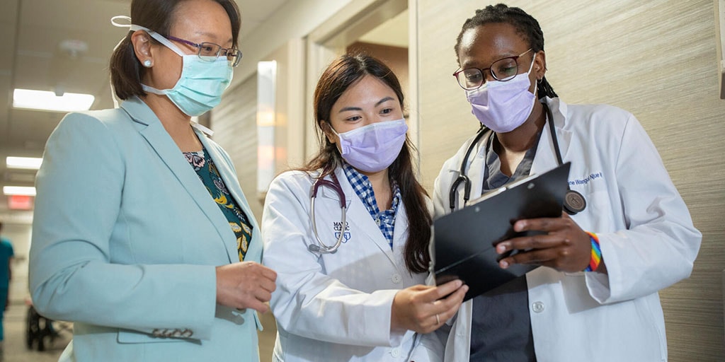 Faculty reviewing a chart with residents in the hallway