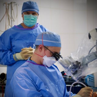 Brian Walker, M.D., ENT resident, looks through a microscope during a trip to Honduras