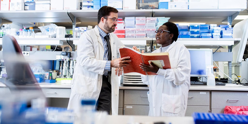 Physician-scientist review information in the lab with Ph.D. student Joanina Gicobi.