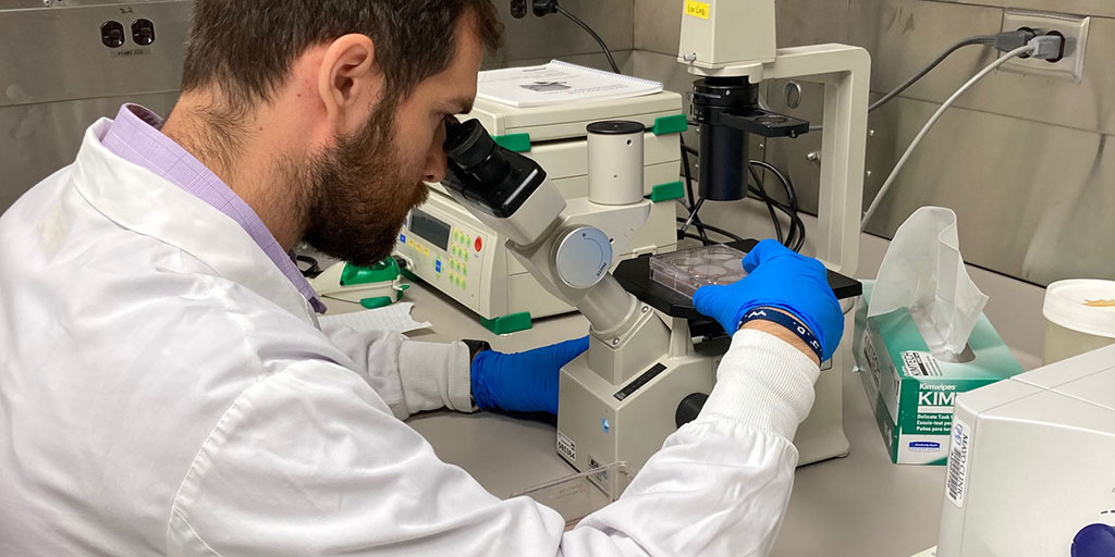 Graduate student Scott Johnson working in the lab with a microscope