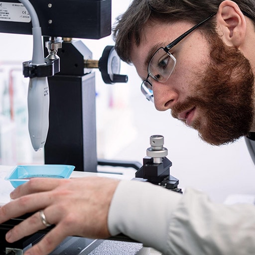 Student looking at sample that's under a microscope