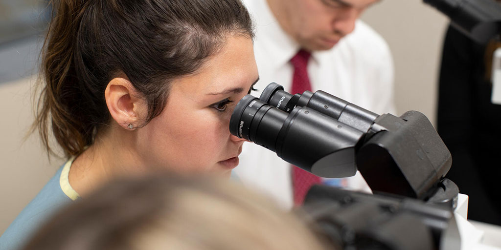 Close up of student's face as she looks into a microscope