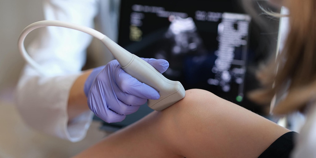 A diagnostic medical sonographer performing a knee ultrasound