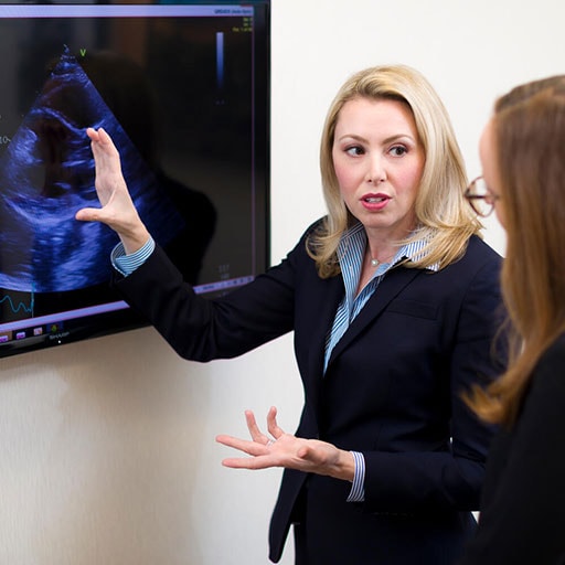 Two fellows in front of large tv screen with echocardiograph on screen