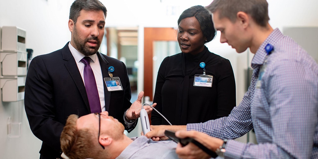 Cardiology nurse practitioners and faculty listen to a patient's heartbeat