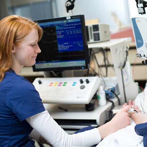 A neurodiagnostic technologist using equipment to test a patient