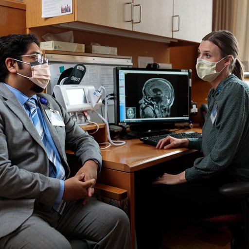 Health care provider sitting at a desk next to patient reviewing a scan on a computer