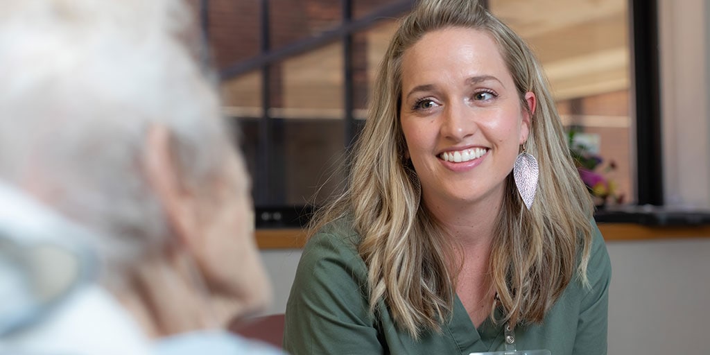 Girl smiling sitting with geriatric patient in a hospital room setting