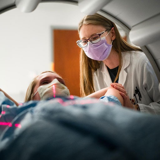 Student getting patient ready for exam with Digital SPECT/CT molecular imaging technology with extendable arms for 3-D imaging of chest organs/cardiac perfusion imaging.