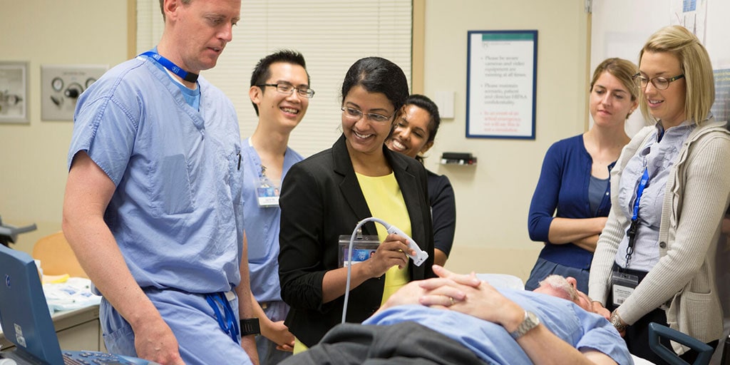 NP or PA fellows learning in a simulation environment with a patient on a hospital bed while they perform ultrasound.