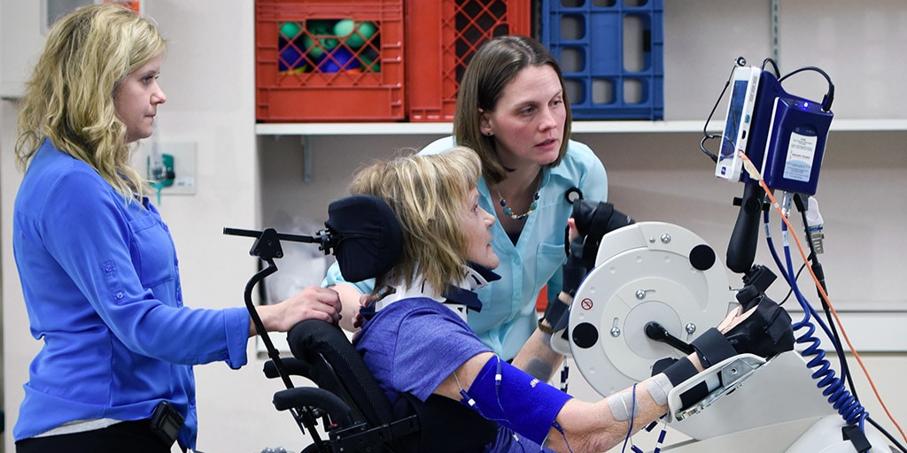 Mayo Clinic occupational therapy students working with patient on exercise machine
