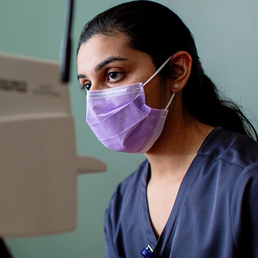 An ophthalmic assistant uses special equipment to preform a test on a patient.