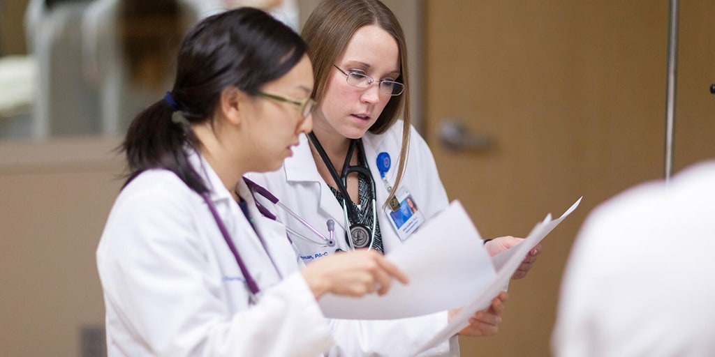 Two physician assistants in the hospital internal medicine fellowship looking over paperwork