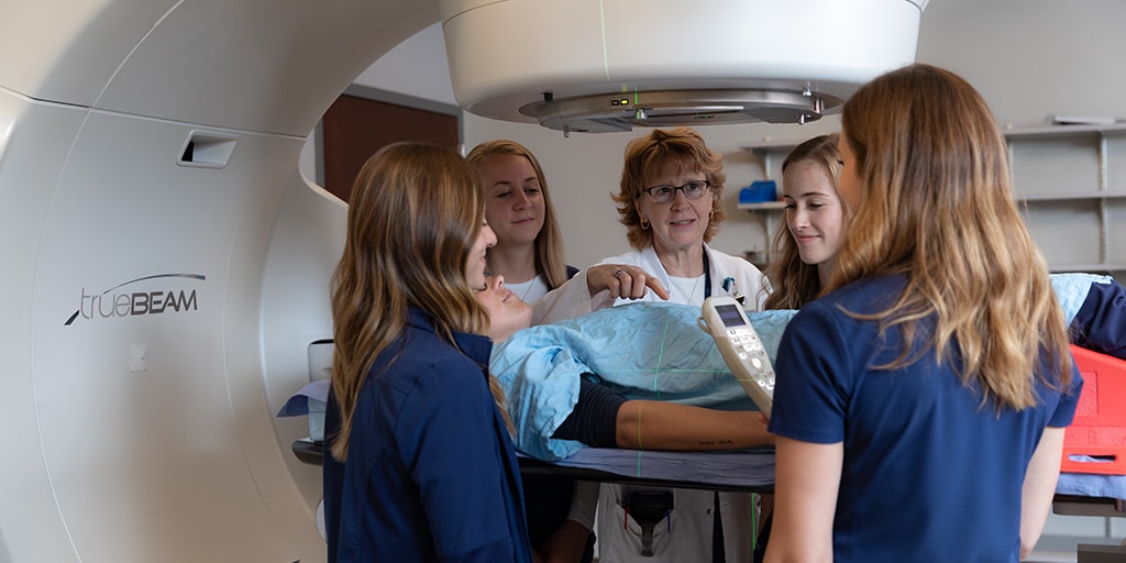 Group of faculty and students practicing radiation therapy on a linear accelerator 