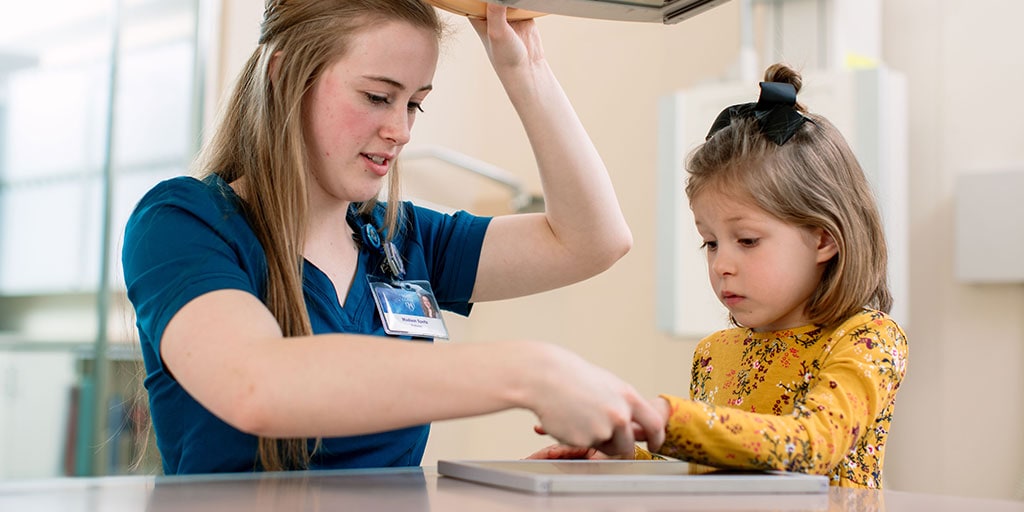 Radiography Program student helping young patient