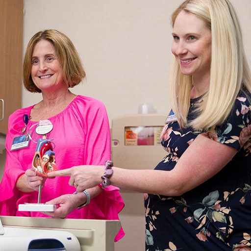 Two Mayo Clinic nurses converse with a patient while showing her an anatomic model of a heart.