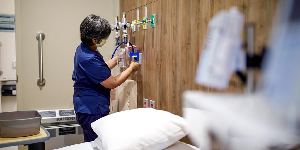 An RN specialized in cancer care sets up an IV in a patient's room
