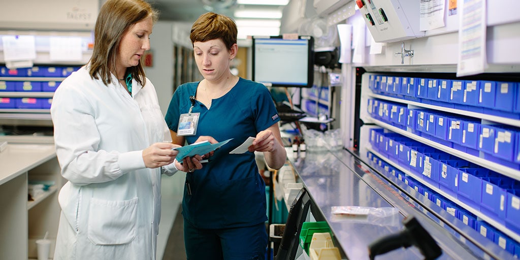 Pharmacists discussing medications in a pharmacy setting.