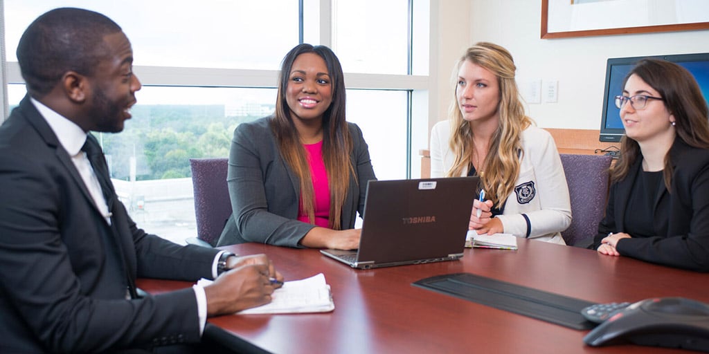 Public Health interns speak to each other around a table in a conference room at Mayo Clinic in Jacksonville, Florida.