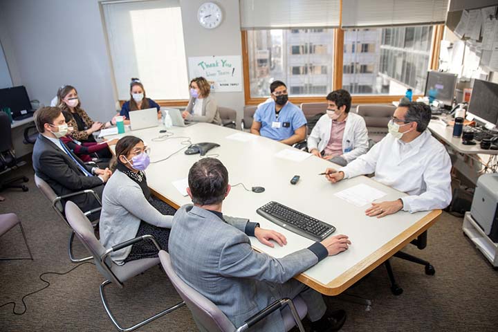 Transplant surgery fellows and faculty in a meeting at a conference table