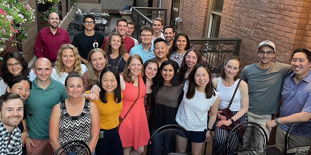 Adult Neurology residents snap a quick group photo outside of a brick building while spending time together at the welcome party for new residents.