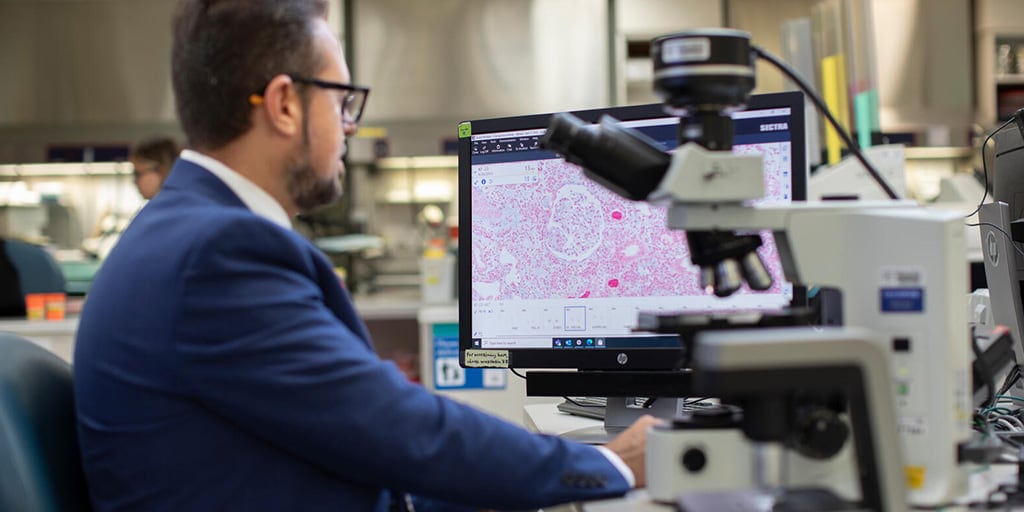 A person from the Anatomic and Clinical Pathology Residency program at Mayo Clinic in Jacksonville, Florida, sat at a desk and used a microscope.
