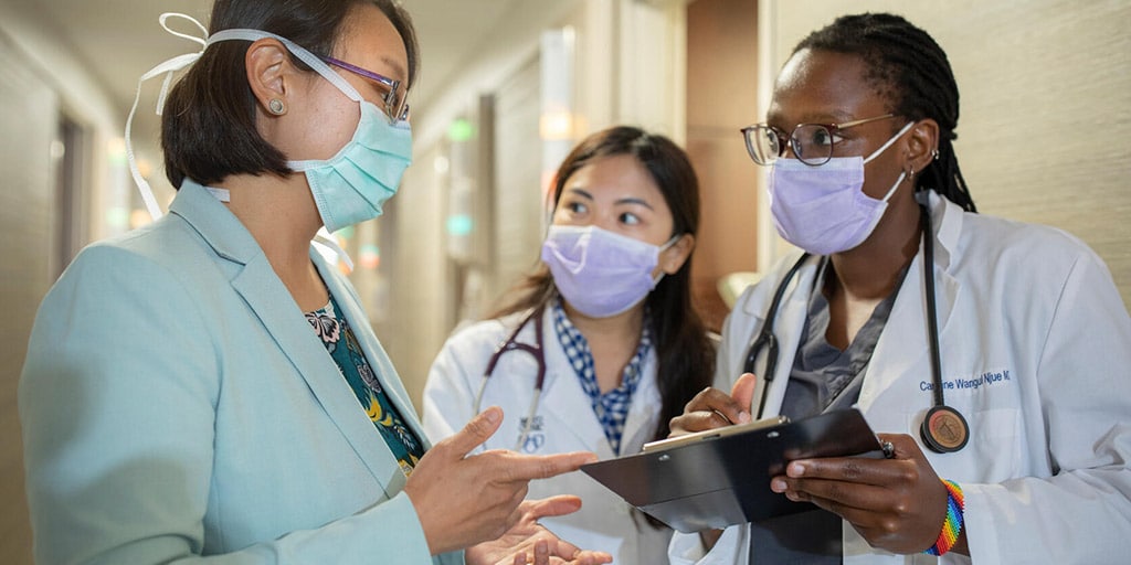 Anesthesia residents collaborating with internal medicine resident in hallway of the postanesthesia care unit at Mayo Clinic in Jacksonville, Florida.
