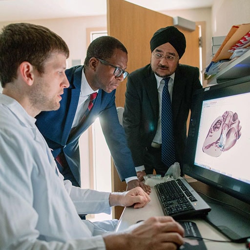 Doctors looking at a heart model on a computer screen.