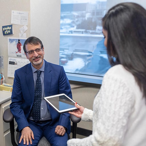 The program director from the Cardiology, Genomics Fellowship in Rochester, Minnesota, at Mayo Clinic School of Graduate Medical Education was in an office and shared information on a digital tablet with a colleague.
