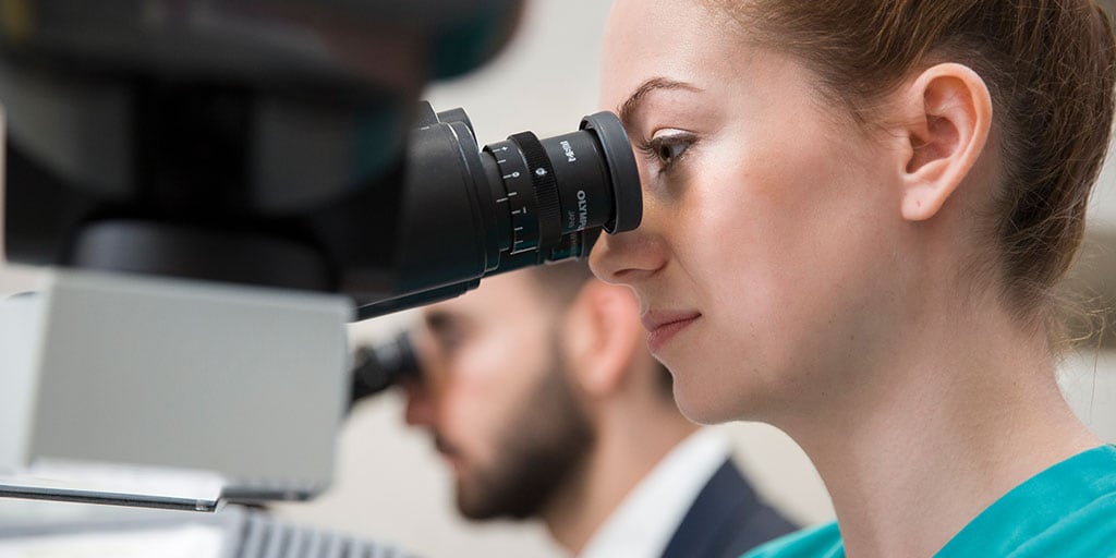 Mayo Clinic dermatology resident in Arizona looking into a microscope