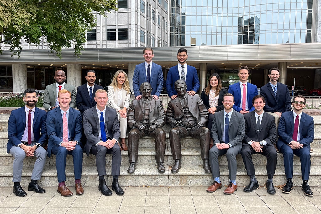 Fourteen people from the Diagnostic Radiology Residency in Rochester, Minnesota, sat around the Mayo brothers statue for a class of 2027 group photo.