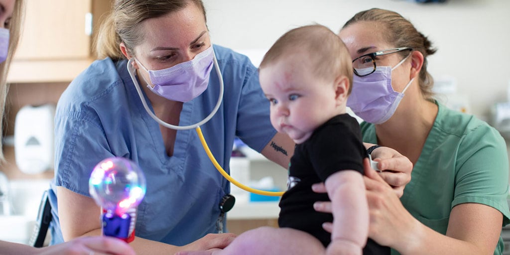 Emergency medicine residents exam a baby in a patient room