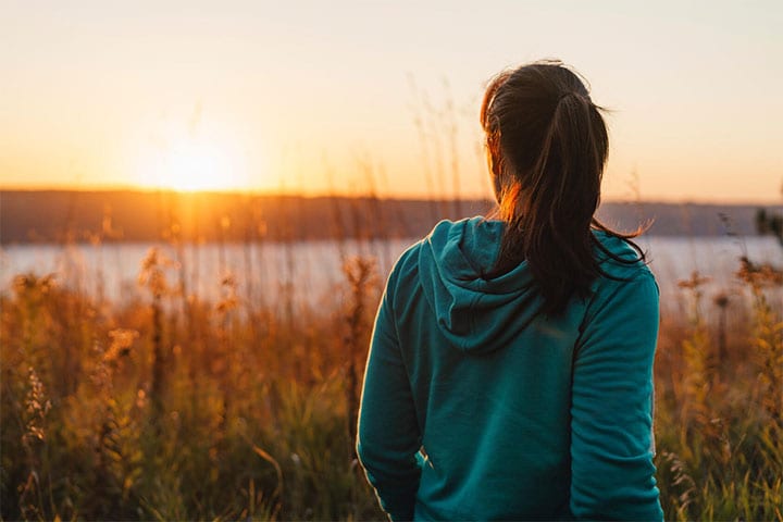 Woman looks out at sunrise over lake in Frontenac State Park.