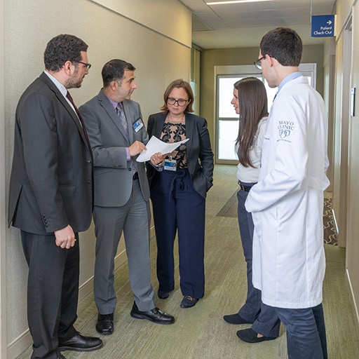 Five doctors from the Hematology/Oncology Fellowship program in Jacksonville, Florida, have a discussion in a hallway.