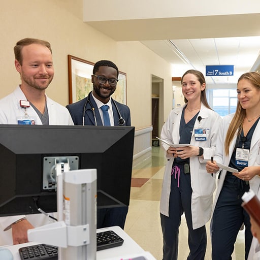 Six residents from the Internal Medicine Residency program in Jacksonville, Florida, gathered around a computer stand while having a discussion.