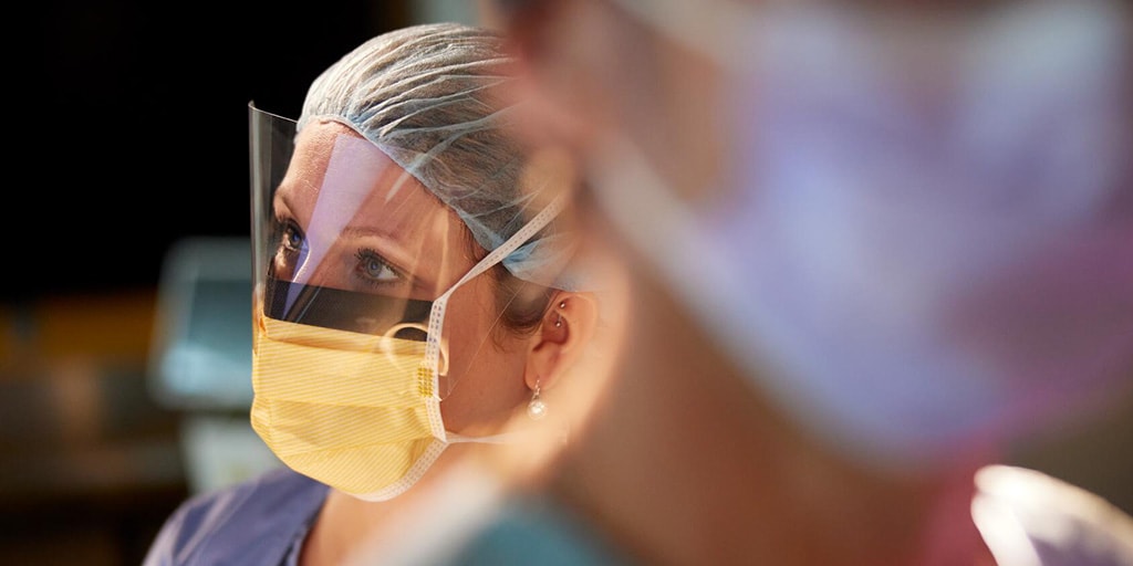 A person dressed in medical surgical attire performing a procedure.