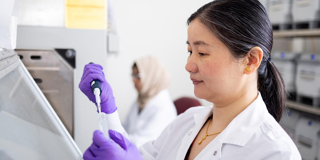 Xia Zhou, MB, PhD, Nephrology fellow, pipettes a sample into a tube in a laboratory.