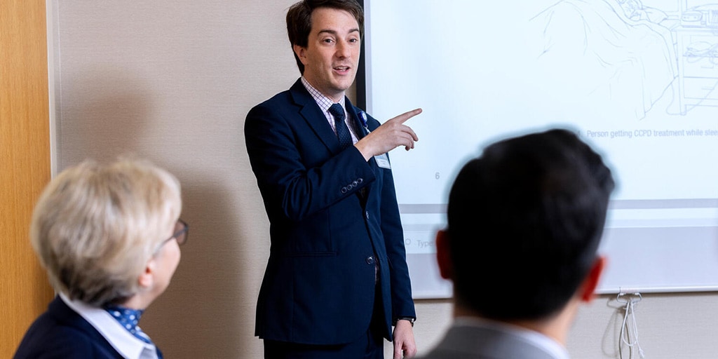 Paul Davis, DO, Nephrology fellow, speaks during a meeting presentation in a conference room.