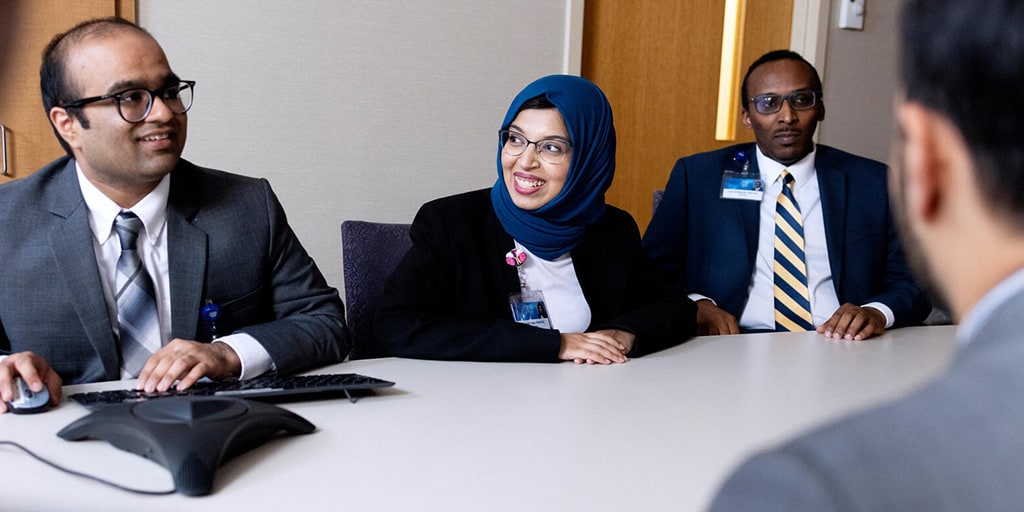 Harshil Fichadiya, MBBS, Nephrology fellow, is shown at a conference table of his colleagues during a meeting where he is presenting.