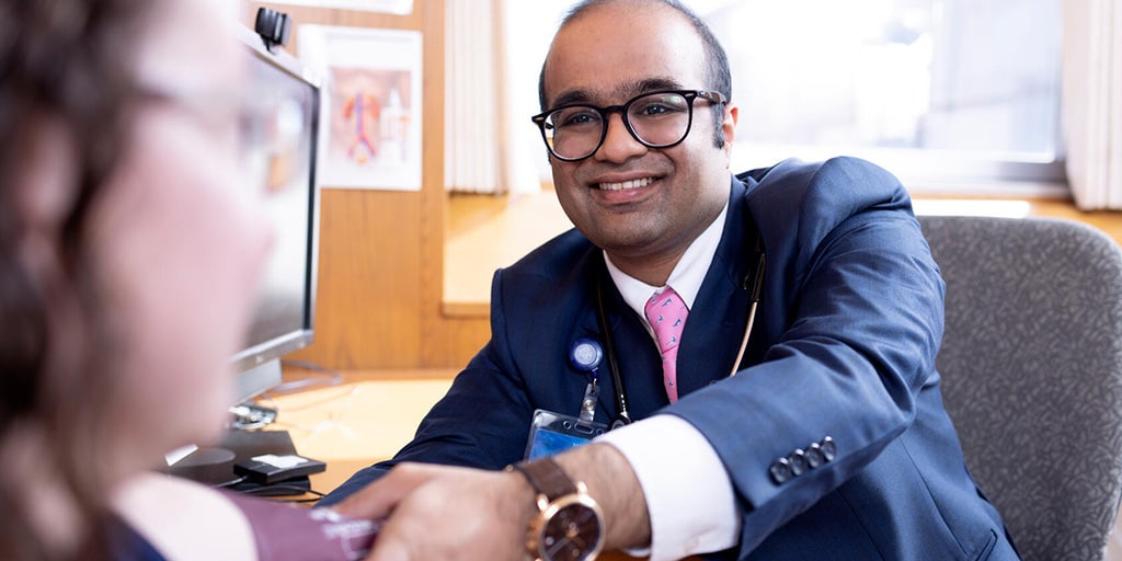 Harshil Fichadiya, MBBS, Nephrology fellow, takes an out-of-frame patient's blood pressure in an exam room.