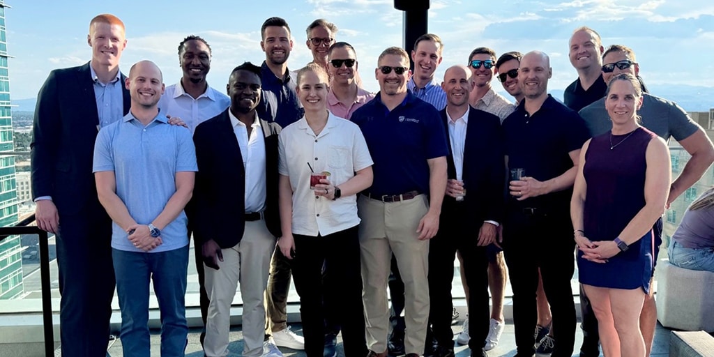 A group of alumni poses outside for a group photo.