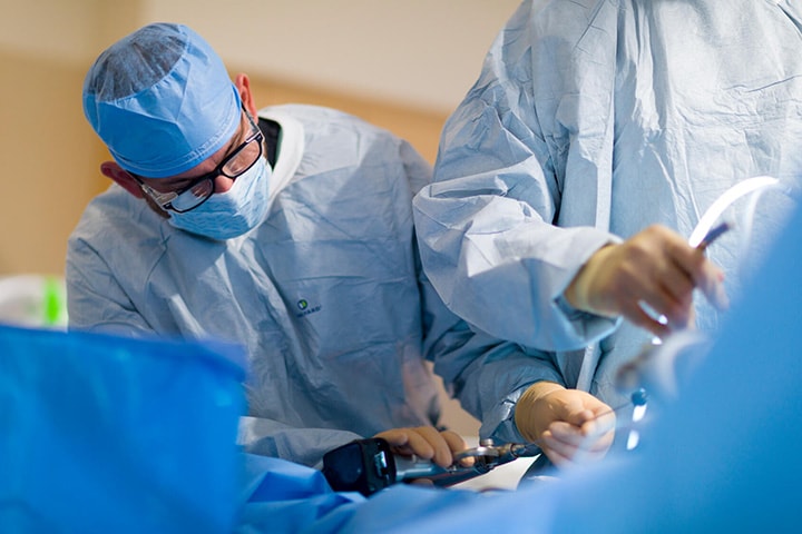 Orthopedic Sports Medicine Fellowship surgeons performing procedure in an operating room.