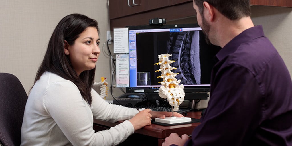 Pain medicine fellow uses model of spine to counsel patient
