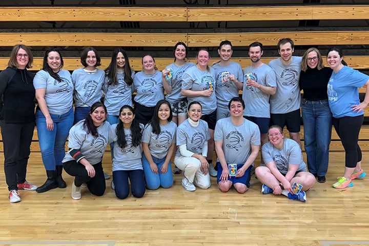 Mayo employees pose for a group shot during a basketball game in a gym.