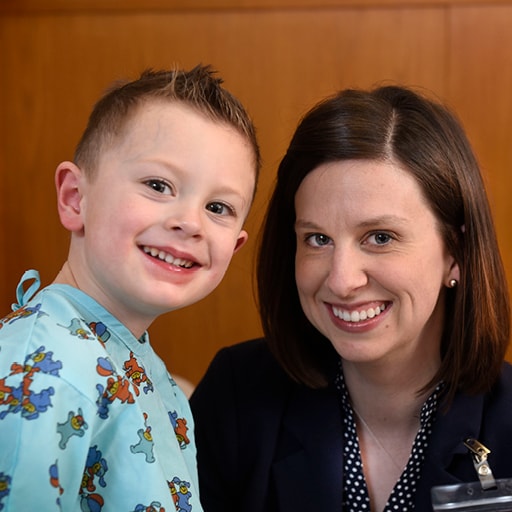 Pediatric Dermatology Fellow poses with a child in the clinic.
