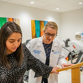 A doctor assists a patient walking in a rehabilitation room.